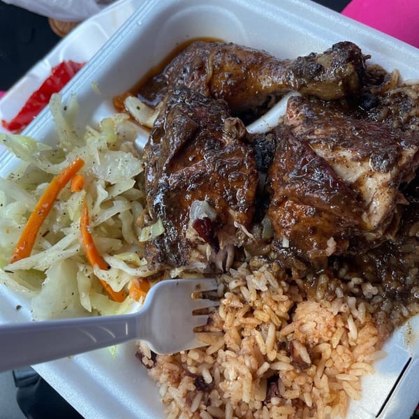 A takeout container with Sunshine Jamaican Restaurant's jerk chicken, rice and peas, and steamed cabbage.